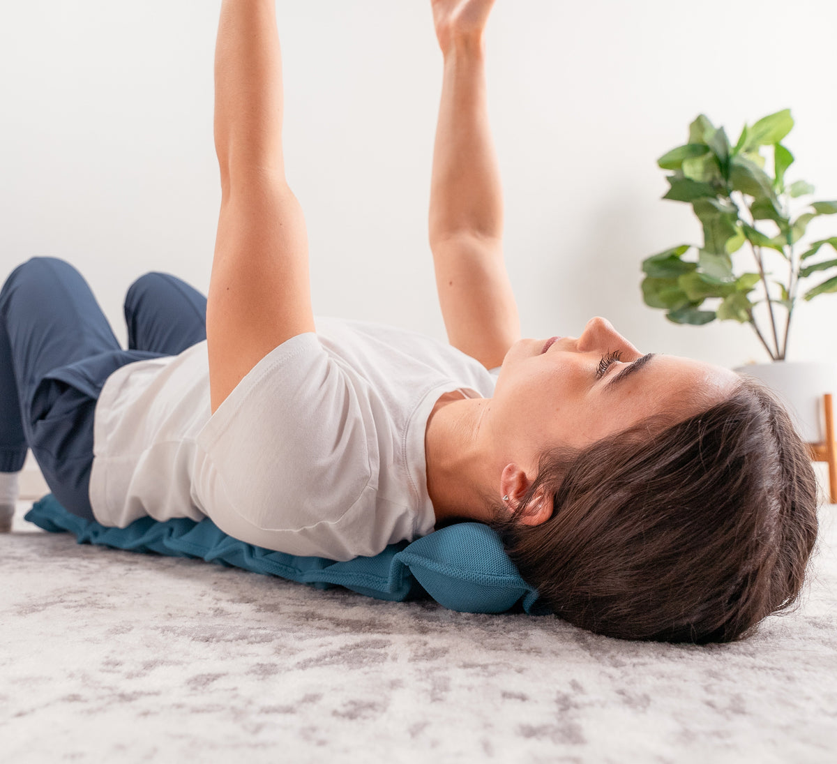 Woman lying on a HALO Spine Stretcher with arms raised, demonstrating a gentle spinal stretching exercise.